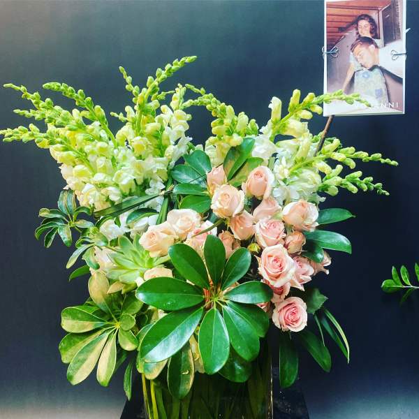 Pink roses and white snapdragons in a vase with glossy green foliage
