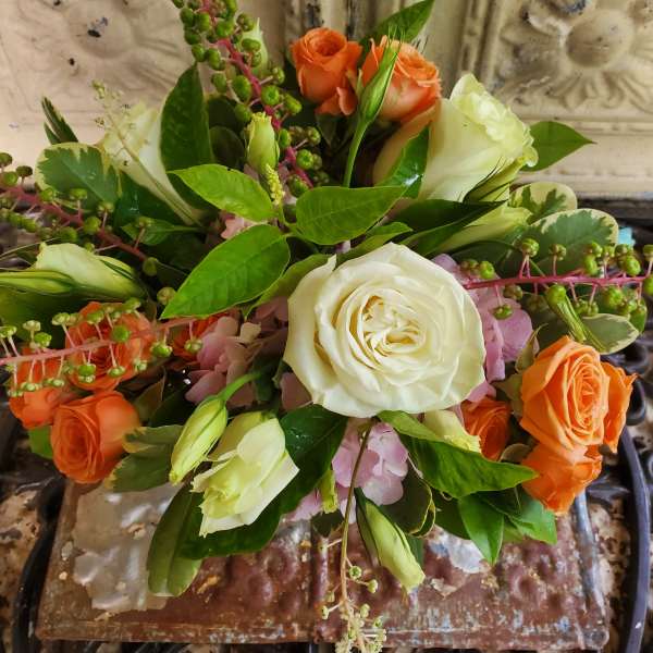 Bouquet of white and orange roses with green berries and pink flowers