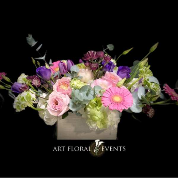 Mixed pink, purple, and green floral arrangement in a square box
