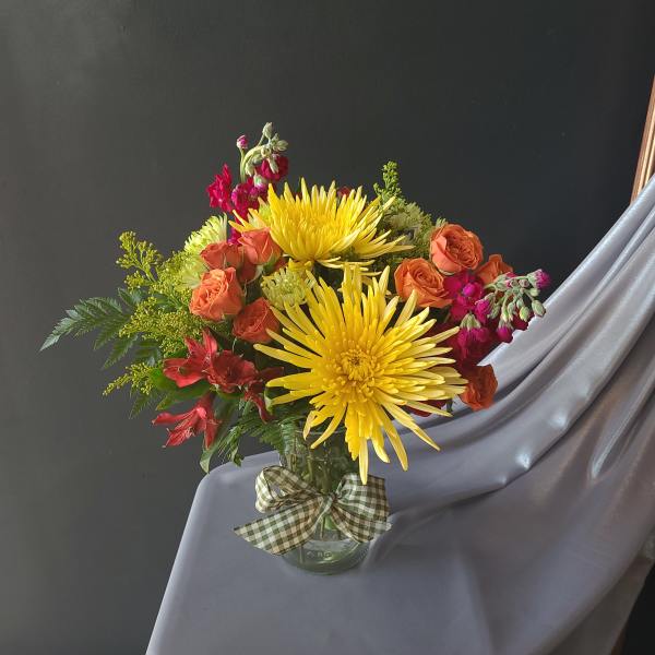 Bouquet of yellow chrysanthemums and orange roses in a glass vase