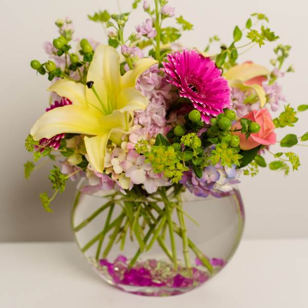 Mixed bouquet with yellow lilies, pink gerbera daisies, and roses in a glass vase