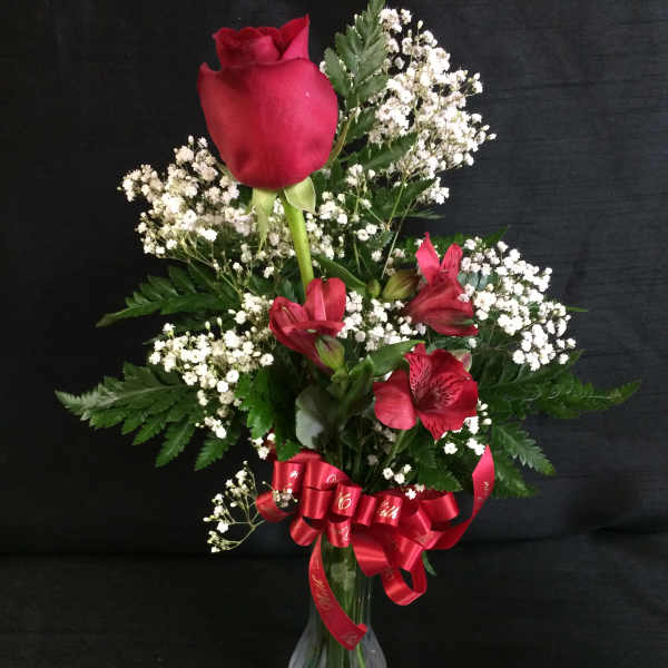 Red rose and alstroemeria bouquet in a glass vase with a red ribbon