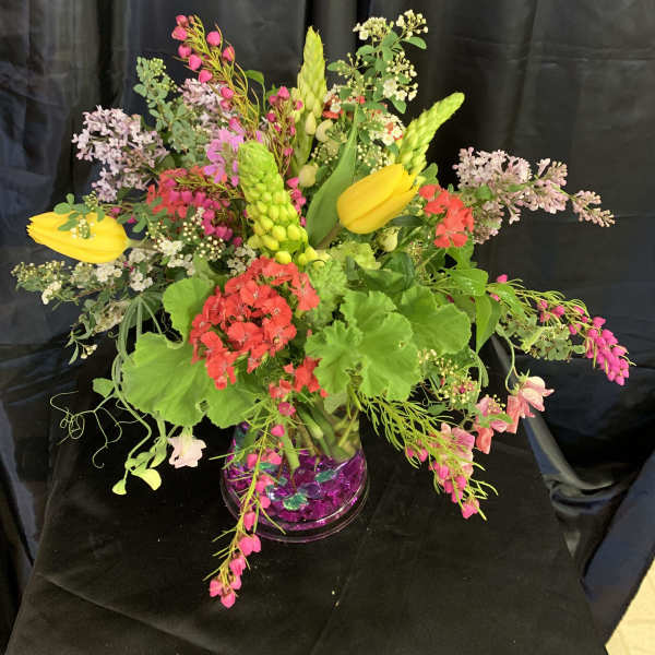 Colorful mixed floral arrangement in a clear vase with yellow tulips