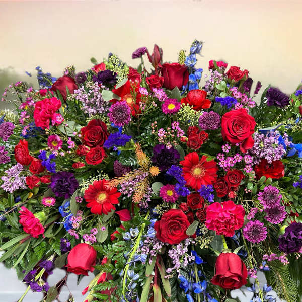 Large mixed floral spray with red roses, purple blooms, and blue flowers