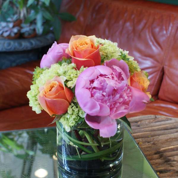 Pink peonies and orange roses in a glass vase