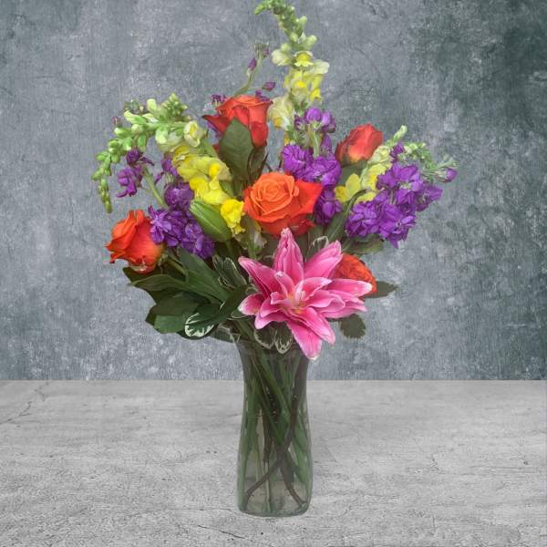Colorful bouquet of roses, lilies, and stock in a glass vase