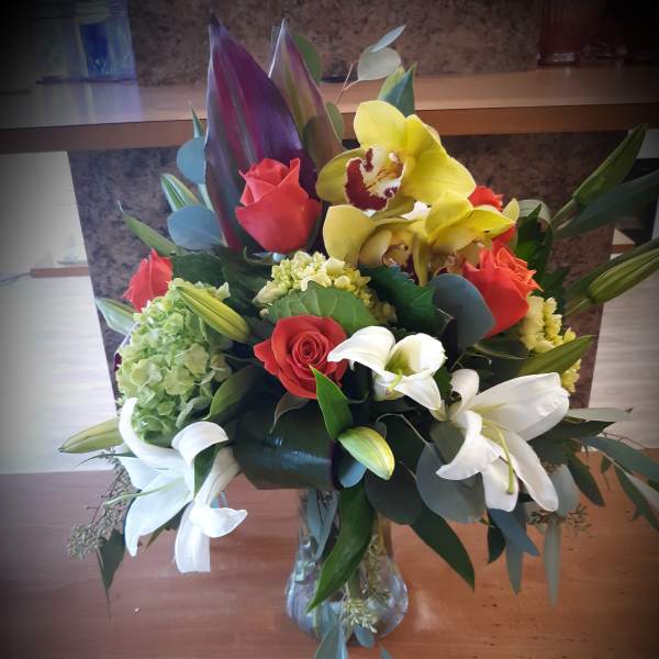 Mixed bouquet with roses, orchids, lilies, and hydrangea in a glass vase