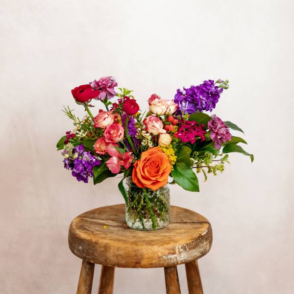 Mixed bouquet of roses and purple flowers in a glass vase
