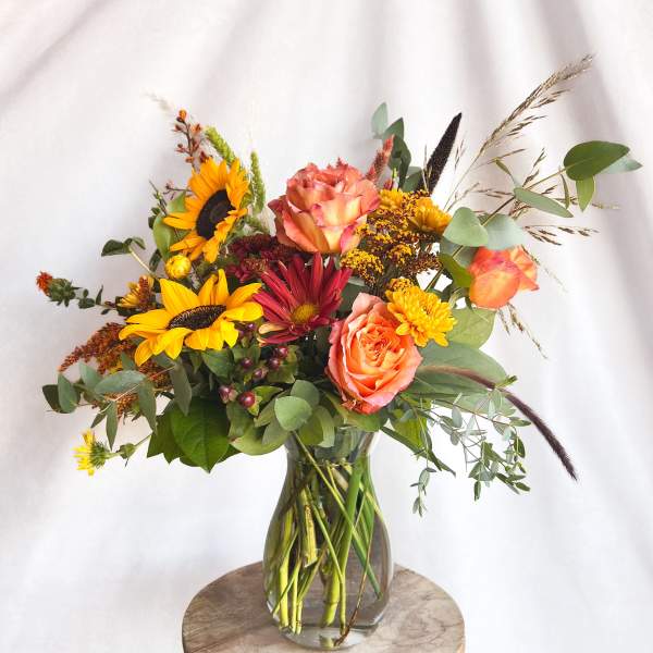 Mixed bouquet in a clear glass vase with sunflowers and peach roses
