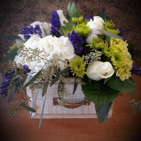Bouquet of white roses, green chrysanthemums, and purple filler flowers in a wooden box