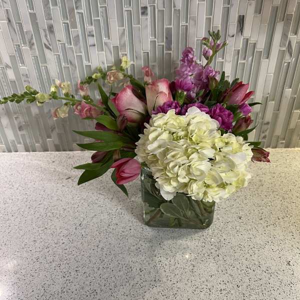 Pink and white floral arrangement in a square glass vase