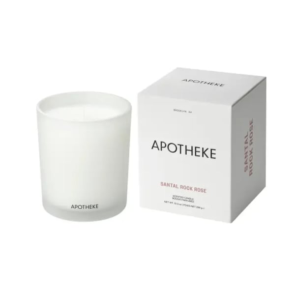 White scented candle in frosted glass jar beside matching Apotheke product box