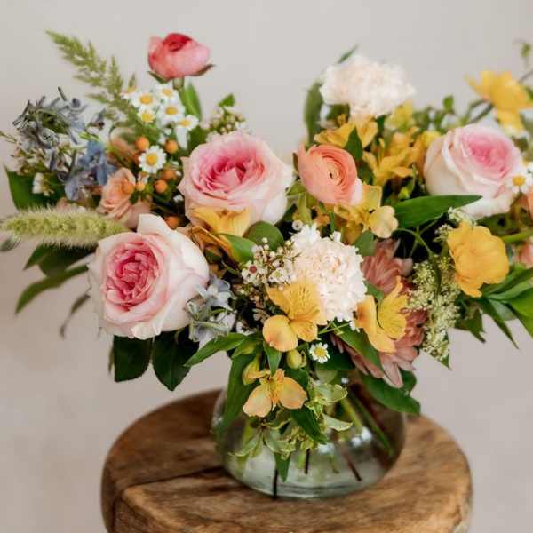 Mixed bouquet of pink and yellow flowers in a glass vase