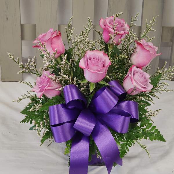 Pink roses arranged with a purple ribbon bow