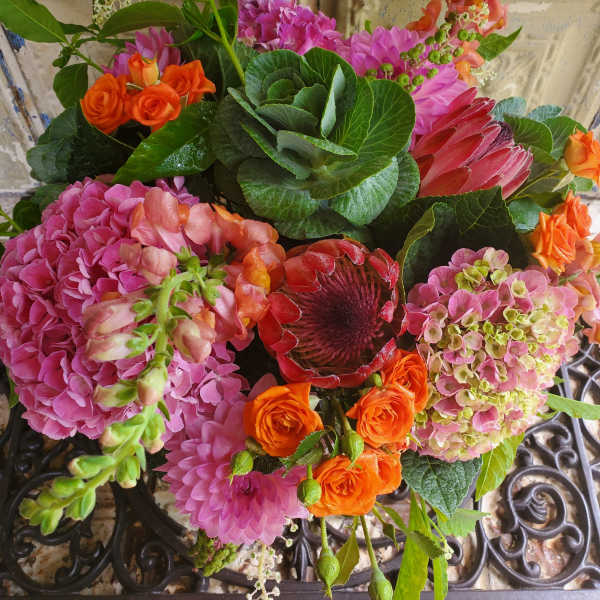Mixed bouquet with pink hydrangeas, orange roses, and a red protea