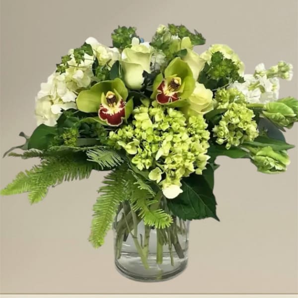 Green and white floral arrangement in a glass vase