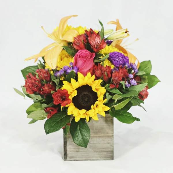Mixed bouquet with a sunflower, pink rose, and yellow lilies in a wooden box