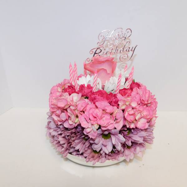 Pink floral birthday cake with candles and a Happy Birthday topper