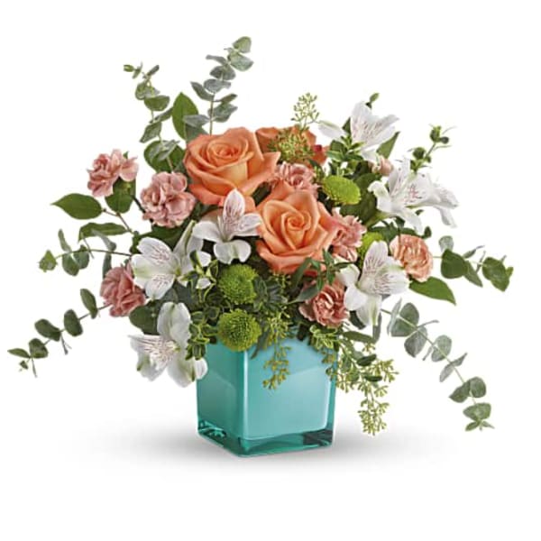 Peach roses and white flowers in a turquoise vase