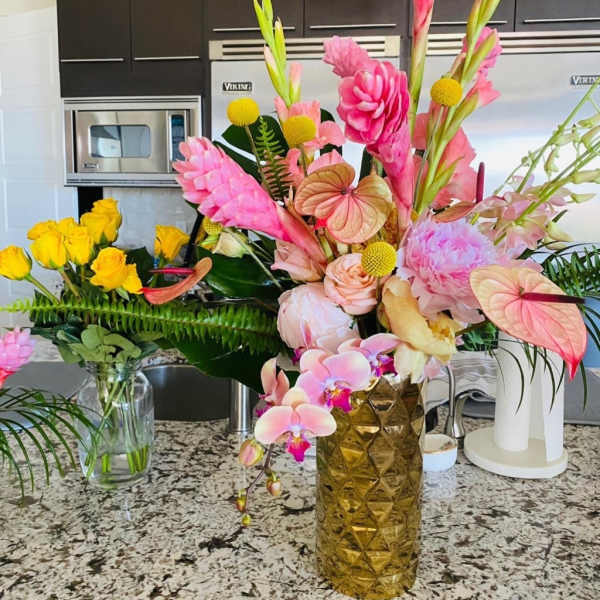 Two colorful floral arrangements in vases on a kitchen counter