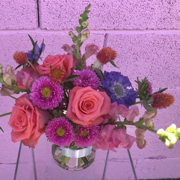 Pink roses and purple flowers in a clear glass vase
