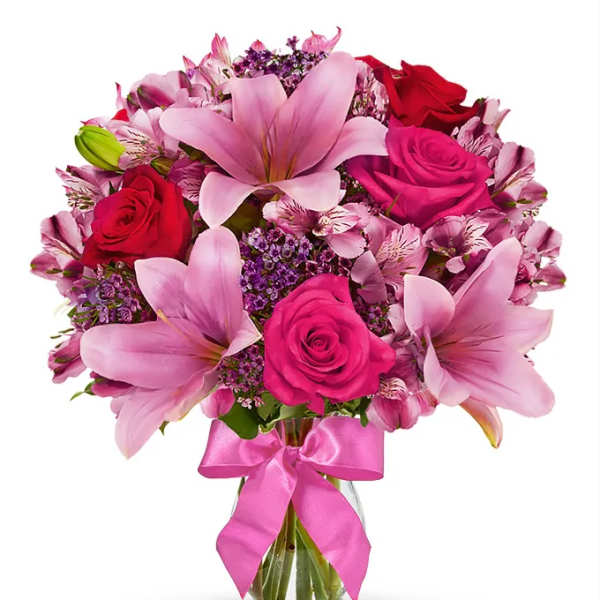 Pink lilies and roses in a glass vase with a pink ribbon