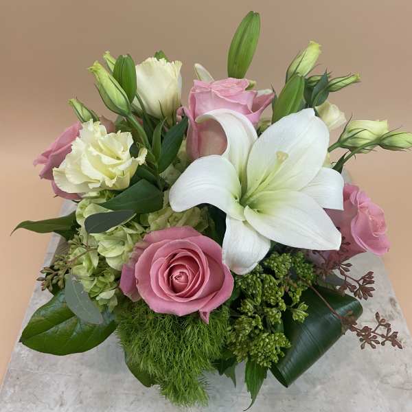 Pink roses and white lilies arranged in a low bouquet
