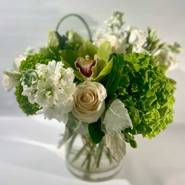 Green and white bouquet with roses and orchids in a glass vase