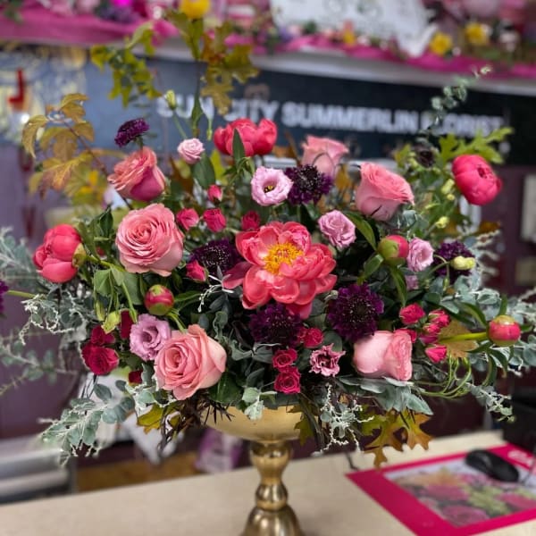 Pink and purple floral arrangement in a gold pedestal vase
