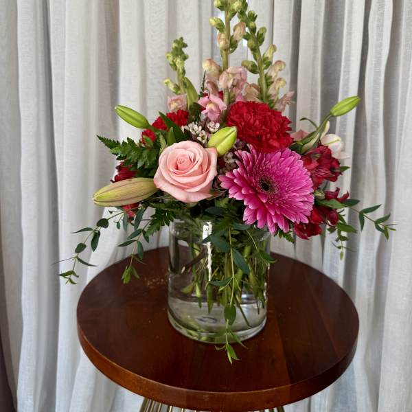 Mixed bouquet in a clear glass vase with pink and red blooms