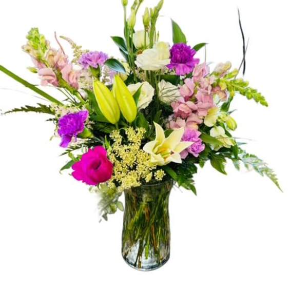 Mixed bouquet of lilies, orchids, and pink flowers in a glass vase