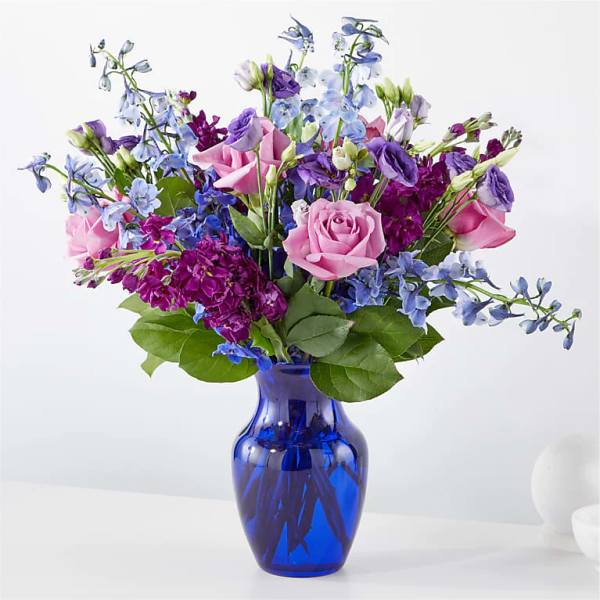 Pink roses and purple-blue flowers in a blue glass vase