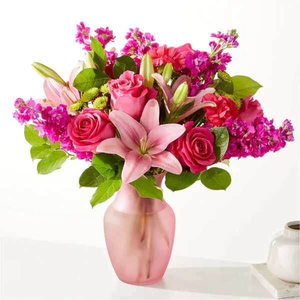 Pink roses and lilies arranged in a frosted pink vase