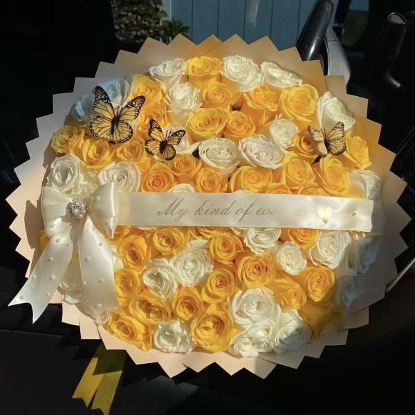 Bouquet of yellow and white roses with butterfly decorations and a satin ribbon