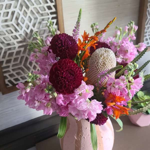 Pink and burgundy floral arrangement in a textured vase