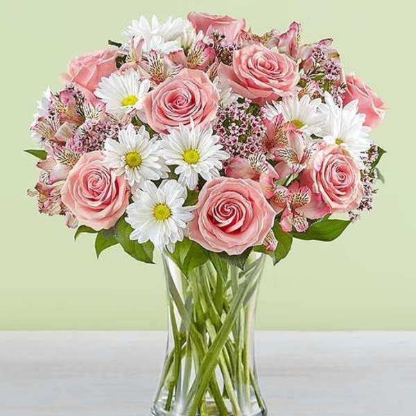 Pink roses and white daisies arranged in a clear glass vase
