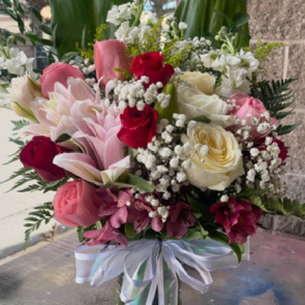 Mixed bouquet of pink and white flowers in a glass vase with ribbon