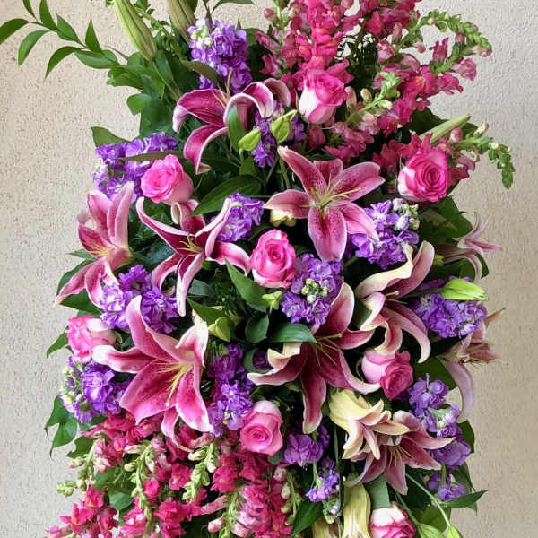 Tall standing floral spray with pink lilies, roses, and purple blooms