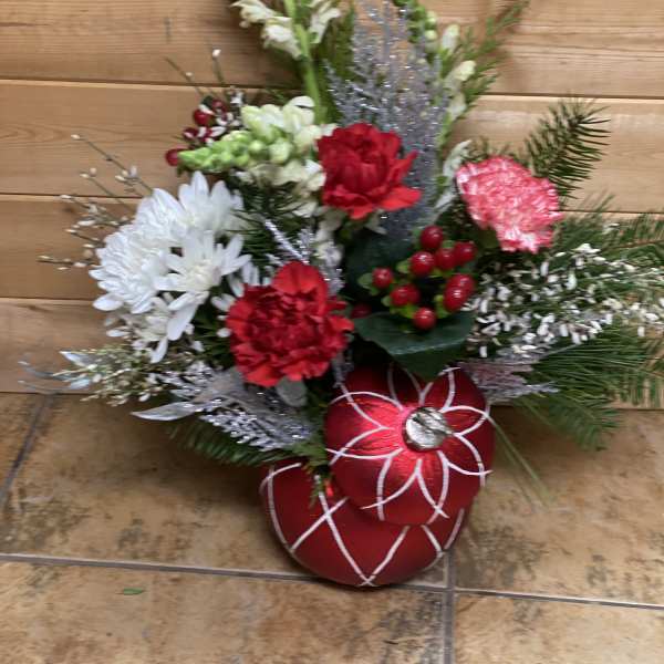 Holiday floral arrangement with red and white blooms and red ornaments