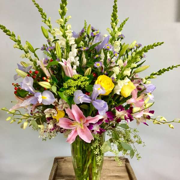 Mixed bouquet of lilies, roses, and orchids in a glass vase