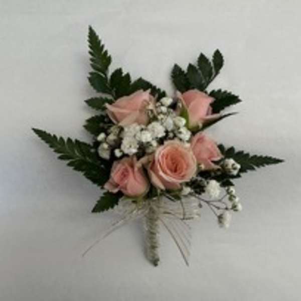 Small pink rose corsage with white baby's breath and dark greenery