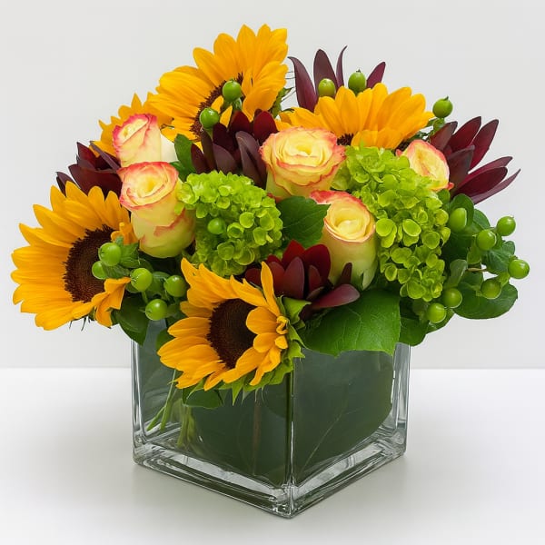 Sunflower and rose arrangement in a square glass vase