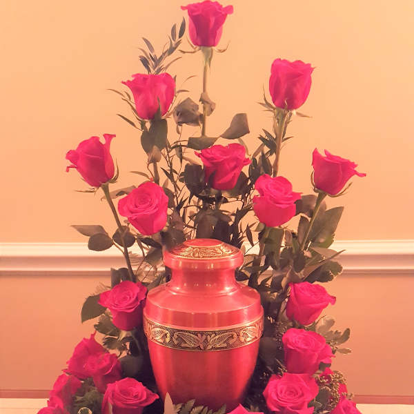 Pink roses arranged around a red urn-shaped vase