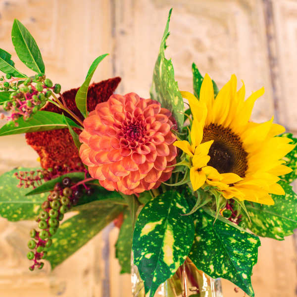 Bouquet with a coral dahlia and yellow sunflower in a glass vase