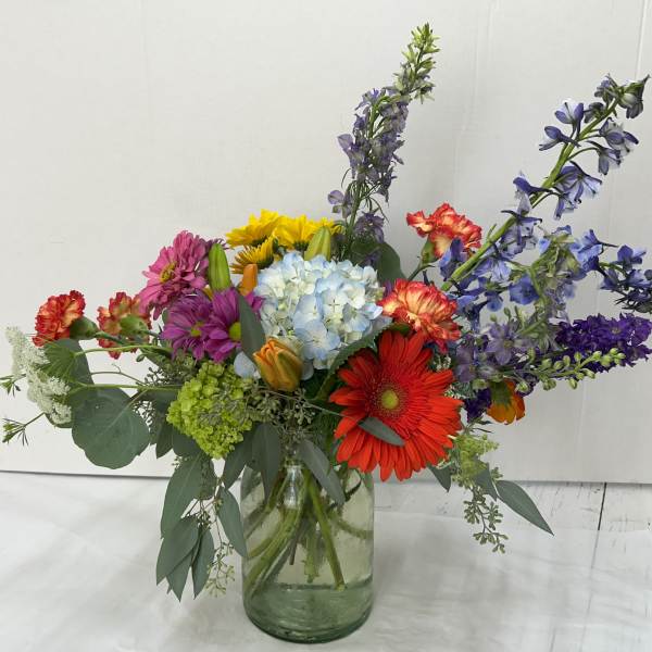 Colorful mixed bouquet in a glass vase with tall purple blooms