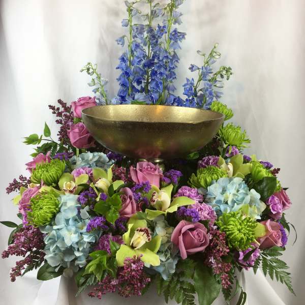 Colorful floral arrangement with a gold bowl centerpiece and tall blue flowers