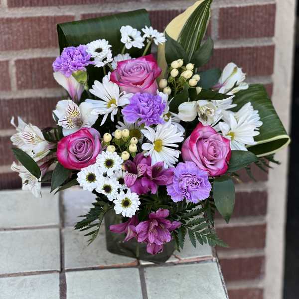 Bouquet of pink roses, white daisies, and purple carnations in a vase