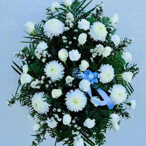 White floral standing spray with roses, chrysanthemums, and a blue ribbon