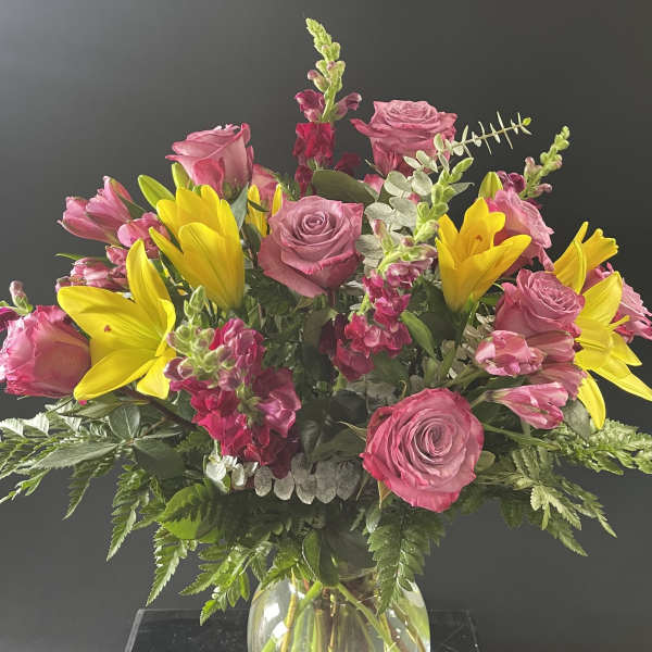 Pink roses and yellow lilies in a clear glass vase