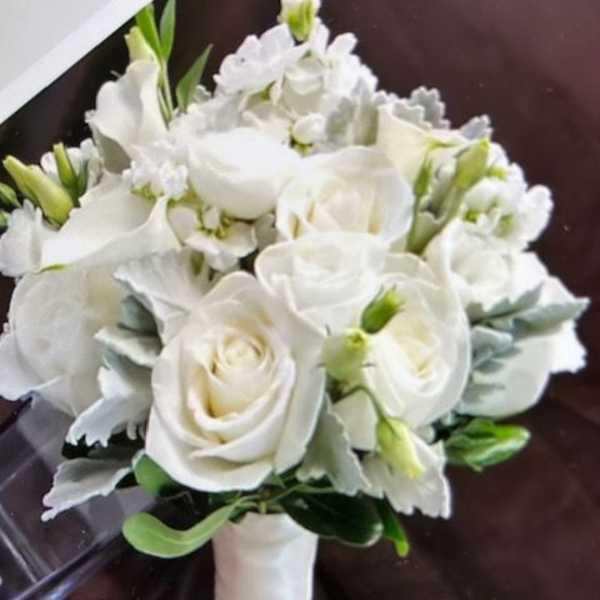 White rose bouquet with small white accent flowers and a wrapped handle